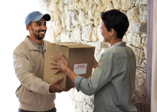 Shot of a smiling young woman standing at her front door receiving a package from a courier.